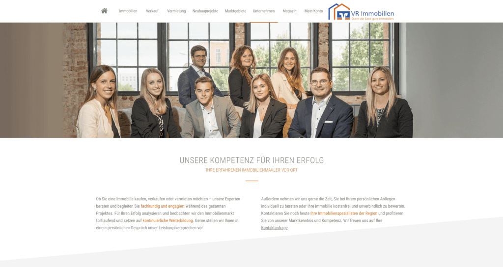 Ein Team von acht Personen steht in einer Reihe vor einer großen Fensterfront und lächelt in die Kamera.
