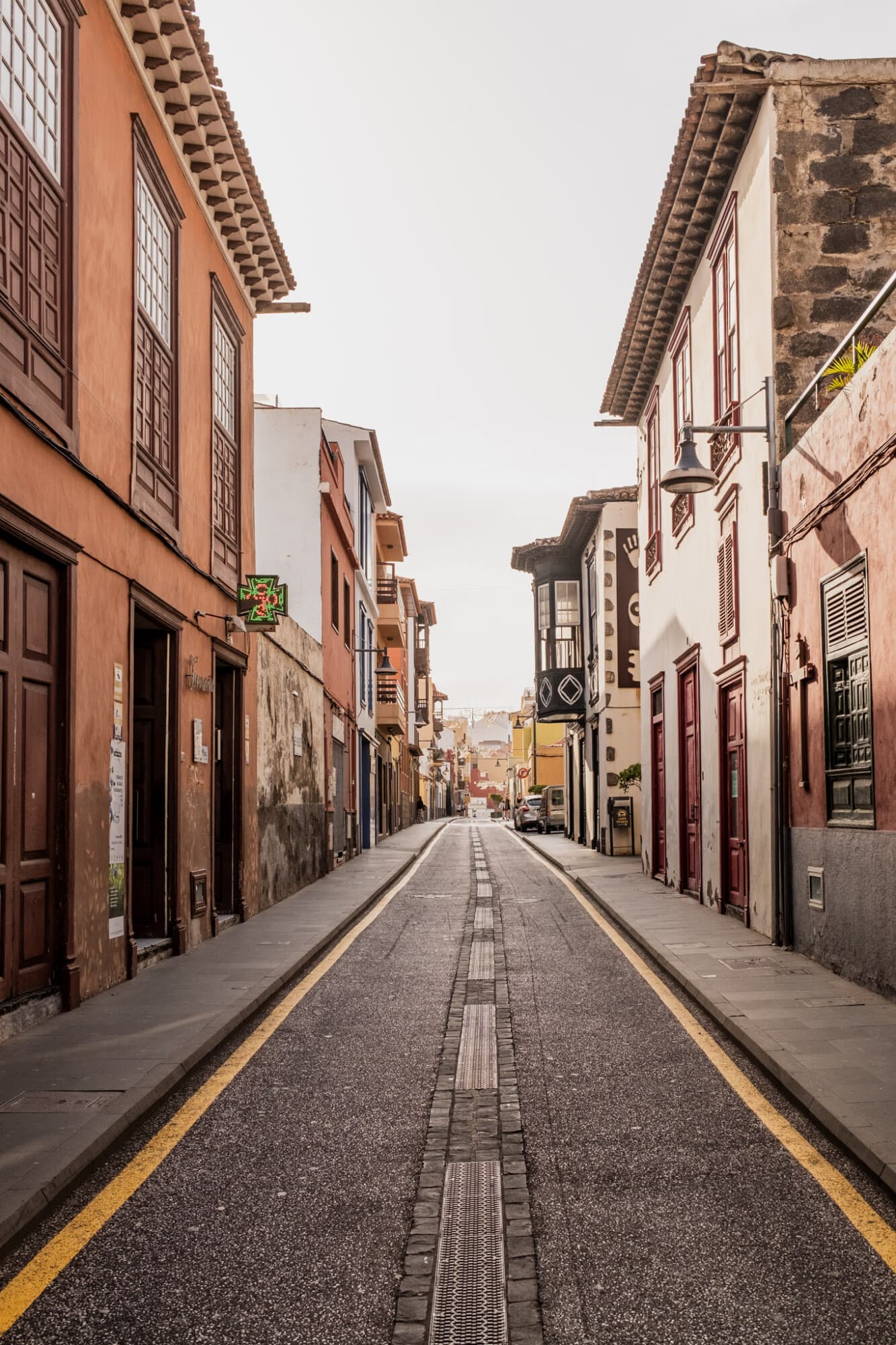 Eine leere, gepflasterte Straße führt mittig durch eine Gasse mit hohen, farbigen historischen Gebäuden.
